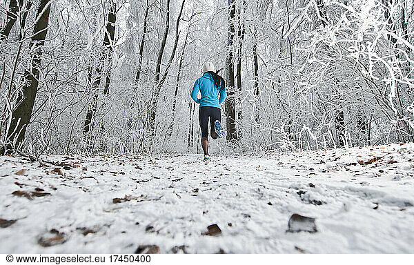 woman running through frosty German forest in Lower Saxony