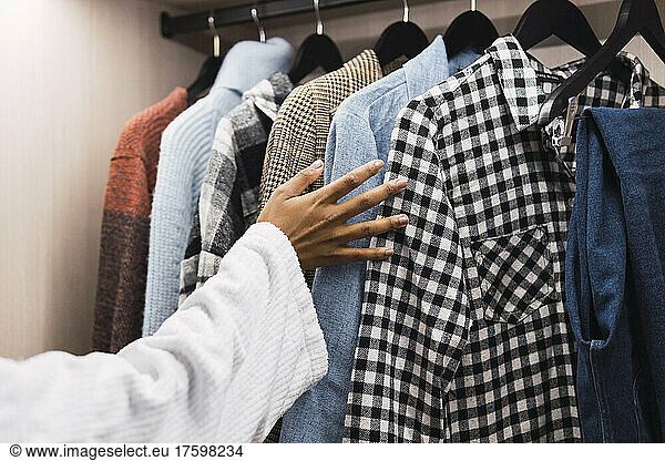 Woman's hand choosing clothes from closet