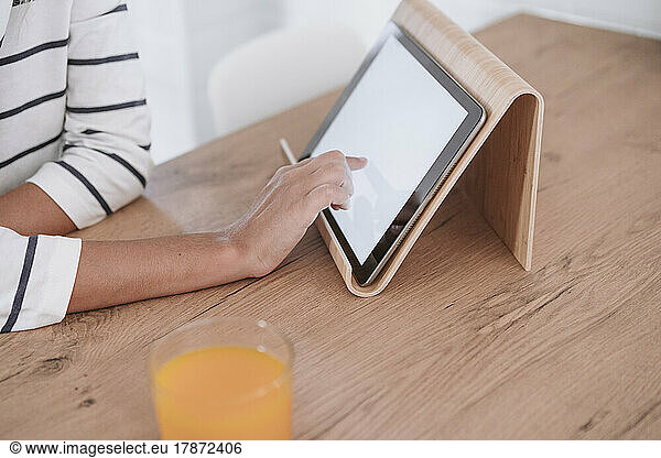 Woman's hand using tablet PC on table at home