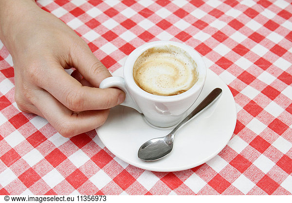 Woman's hand with espresso at sidewalk cafe table  Milan  Italy