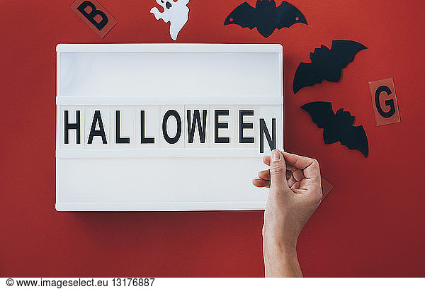 Woman's hands adding letter at 'Halloween' sign