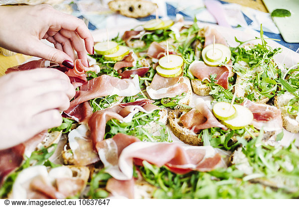 Woman's hands placing meat slices on open faced sandwiches