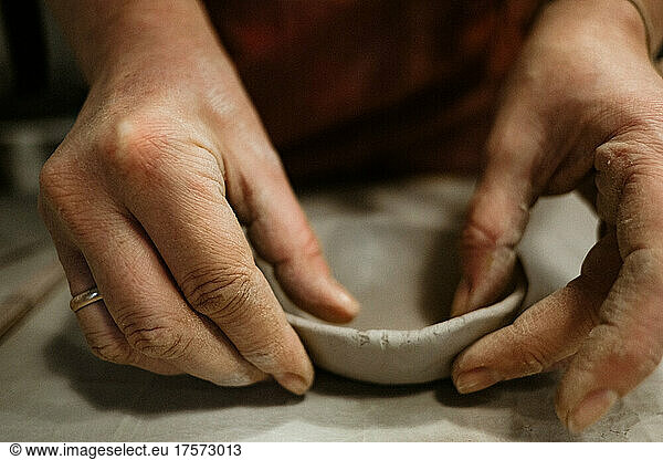 Woman's hands works with clay on the table