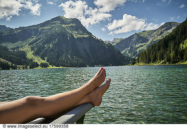 Woman's legs on prow of rowboat in lake