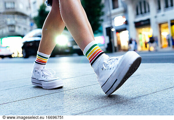 woman's legs walking down the street with a car in the background
