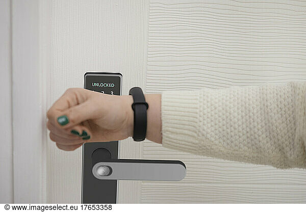 Woman scanning smart watch to open door of house