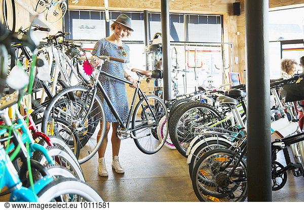 Woman selecting bicycle from rack in bicycle shop