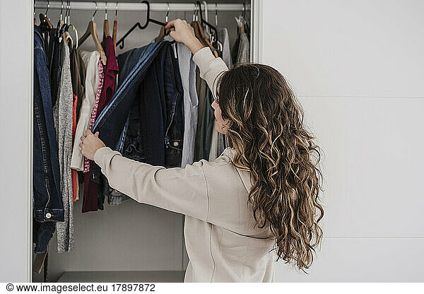 Woman selecting clothes from closet at home