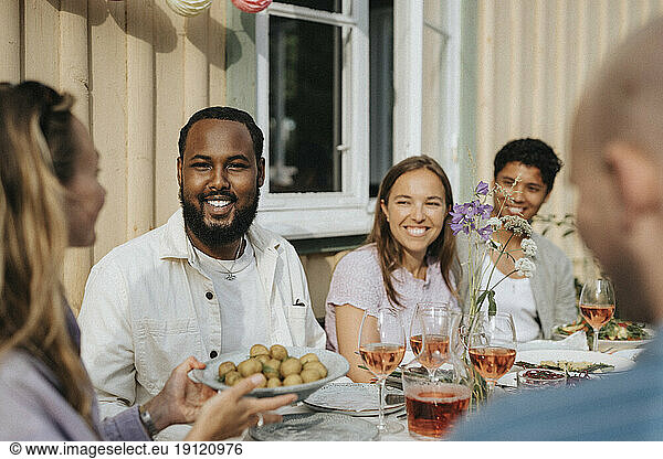 Woman serving baby potatoes to male and female friends during dinner party at cafe