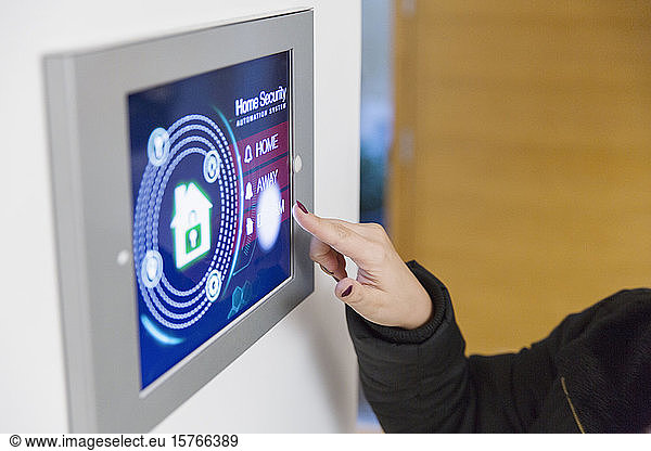 Woman setting smart home security alarm at touch screen