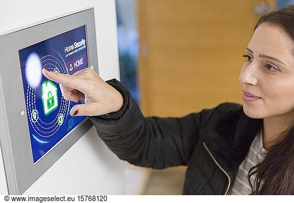 Woman setting smart home security alarm at touch screen