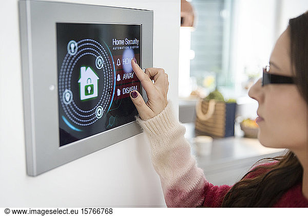 Woman setting touch screen home alarm system