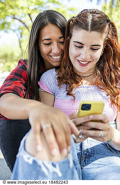 Woman sharing mobile phone with girlfriend