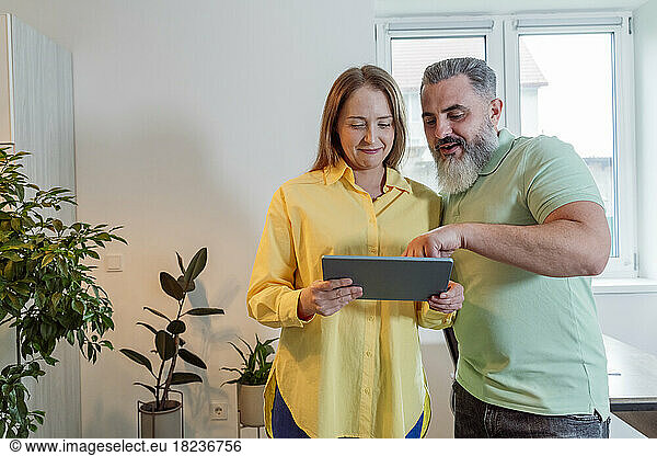Woman sharing tablet PC with bearded man at home