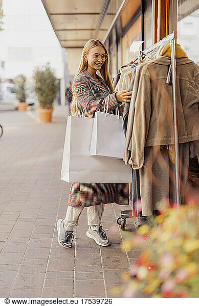 Woman shopping clothes hanging on rack outside store