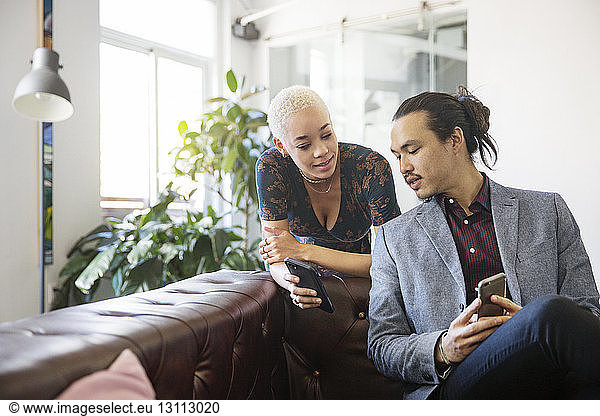 Woman showing mobile phone to colleague in office