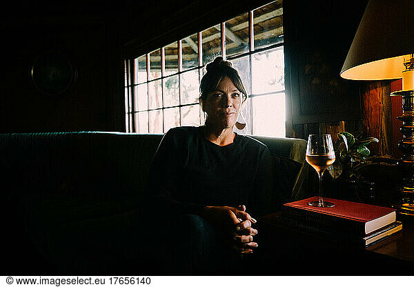Woman Sits in Cozy Cabin With Glass of Rose