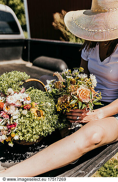 Woman sits on truck bed arranging fresh garden flowers