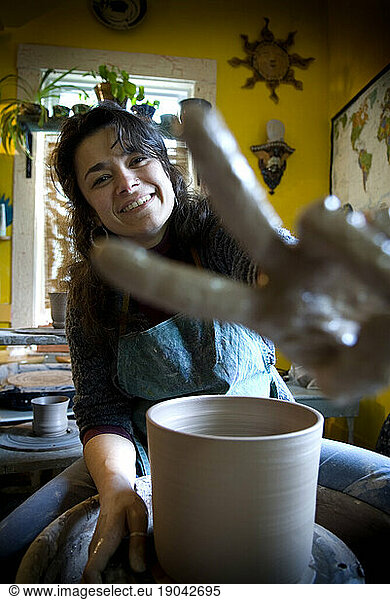 Woman sitting at a ceramics wheel.