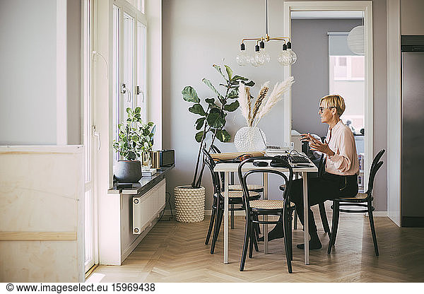 Woman sitting at table having an online meeting working at home