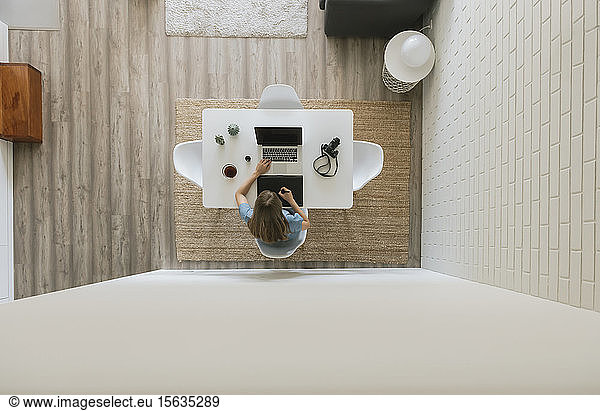 Woman sitting at table working on graphics tablet and laptop top view
