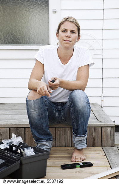 Woman sitting by tool box in front of house
