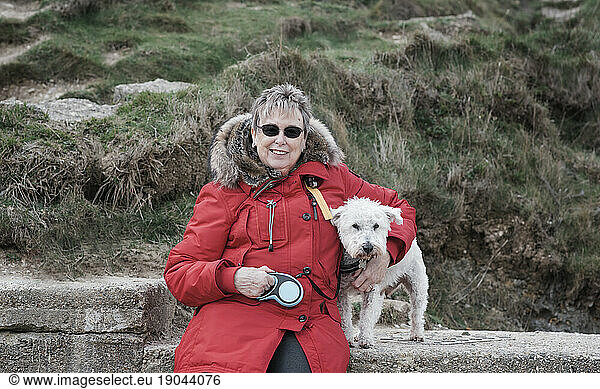 woman sitting hugging her dog at the beach in winter