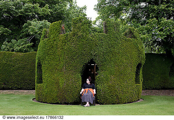woman sitting in a bush cut out as a thrown in the English countryside