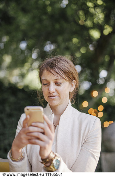 Woman sitting in a garden  using her mobile phone.