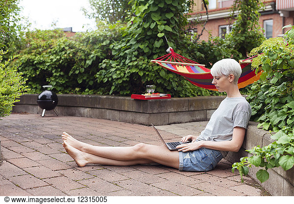 Woman sitting in garden and using laptop