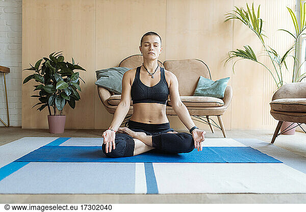 woman sitting in yoga lotus pose at home