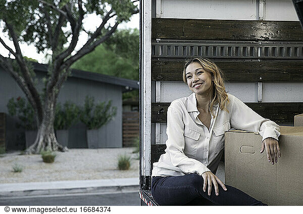 Woman Sitting Inside Moving Truck with Boxes