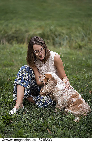 Woman sitting on a meadow with her dog
