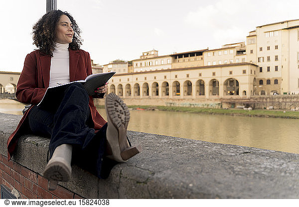 Woman sitting on a wall at River Arno  Florence  Italy
