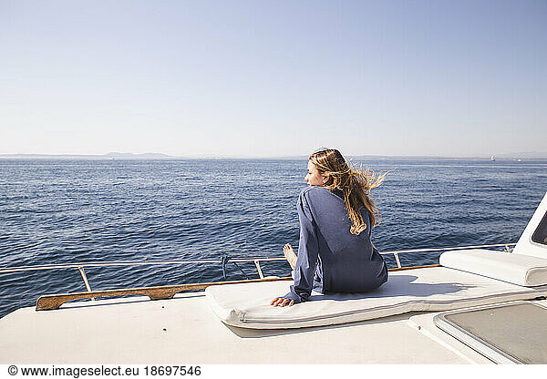 Woman sitting on boat deck at sunny day