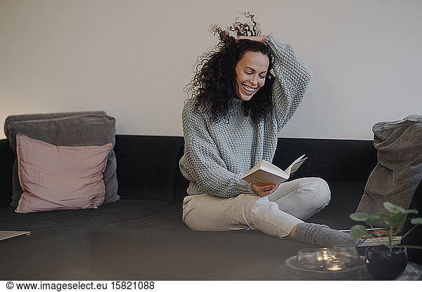 Woman sitting on couch  having fun  reading a book