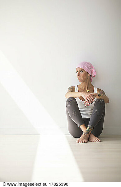 Woman sitting on floor in yoga studio on sunny day