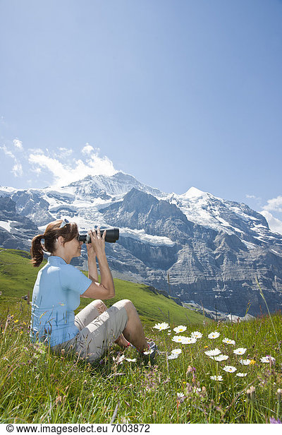 Woman Sitting on Mountain Side using Binoculars  Bernese Oberland  Switzerland