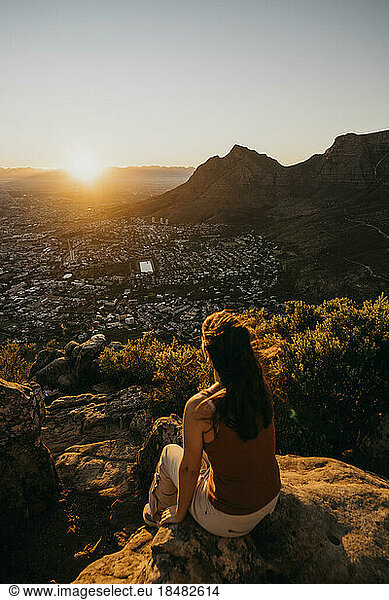 Woman sitting on rock looking at cityscape from Lion's Head Mountain