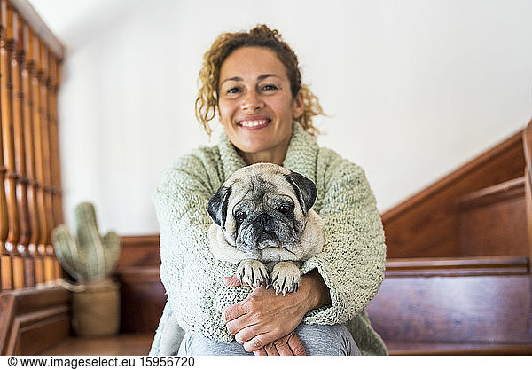 Woman sitting on stairs  with pug on her lap