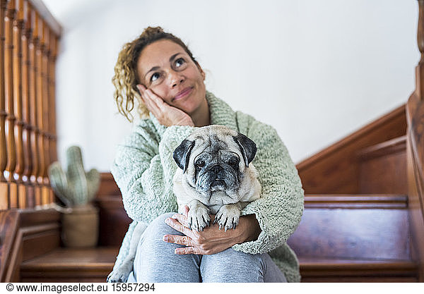 Woman sitting on stairs  with pug on her lap