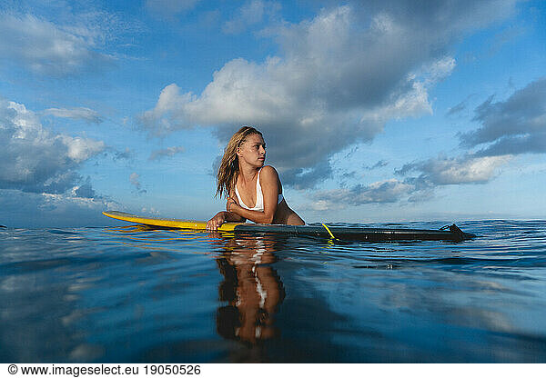 Woman sitting on surfboard in the sea