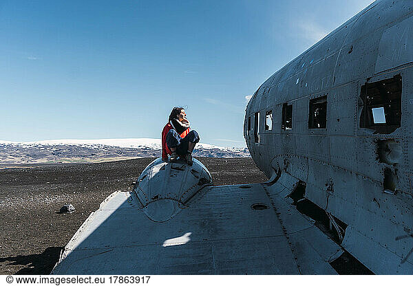 woman sitting on the wing of a lost plane