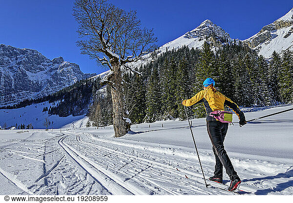 Woman skiing on snowy landscape towards Karwendel Mountains