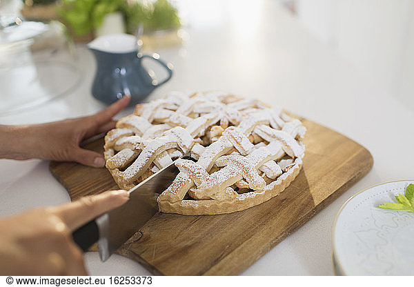 Woman slicing fresh homemade baked lattice pie