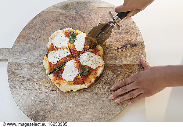 Woman slicing fresh homemade pizza on cutting board