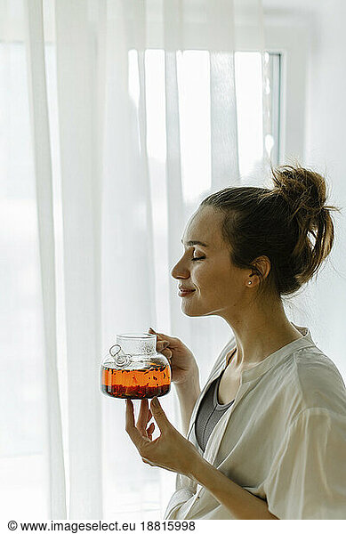 Woman smelling freshly brewed tea at home