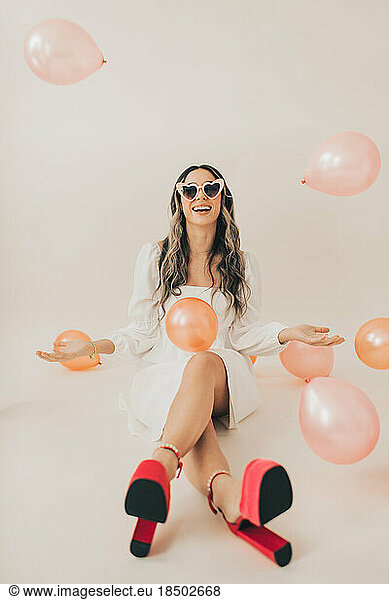 Woman Smiling Wearing Sunglasses While Throwing Balloons in Air