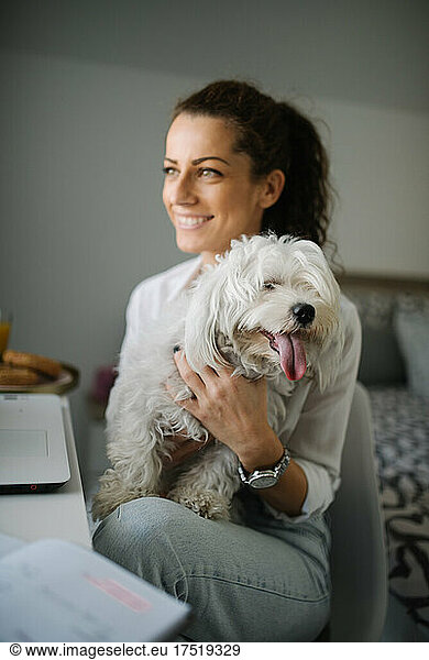Woman smiling while petting a dog in her lap.