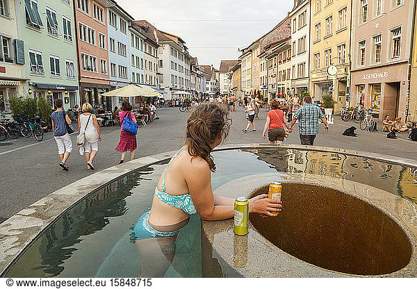 Woman soaks and drinks in outdoor fountain  Winterthur  Switzerland